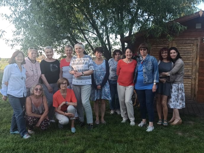 Zdjęcie przedstawiające grupę kilkunastu kobiet stojący w ogrodzie